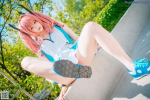 A woman with pink hair sitting on a concrete ledge.