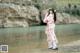 A woman in a pink kimono standing by a river.