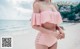 A woman in a pink bikini standing on a beach.