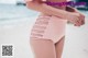 A woman in a pink bikini standing on a beach.