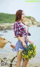 A woman standing next to a bike holding a bunch of flowers.