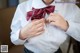 A woman in a white shirt is adjusting a red bow tie.