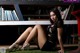 A woman sitting on the grass in front of a bookshelf.