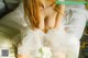 A woman in a wedding dress sitting on a bed.